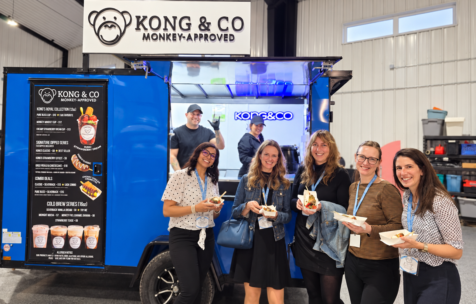 Happy guests and Kong&Co team smiling in front of the blue trailer at a corporate event